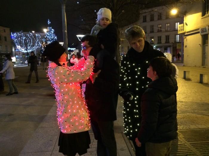 Des êtres vêtus de lumières interagissent avec les personnes dans les rues