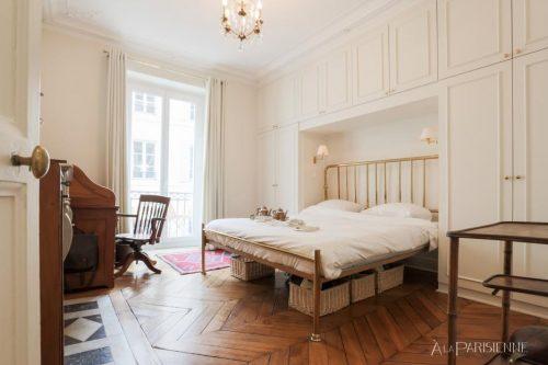 La chambre a un lit double taille maître (180x200), une armoire, un bureau et un balcon avec vue sur la rue.